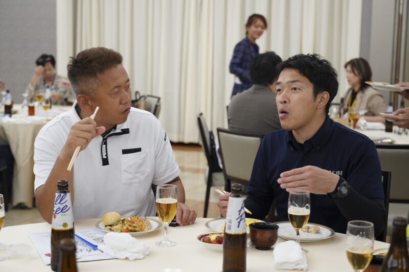 食事の席で会話を交わす二人の男性参加者