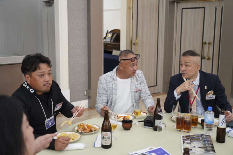 三人で食事をしながら事業の話をする様子