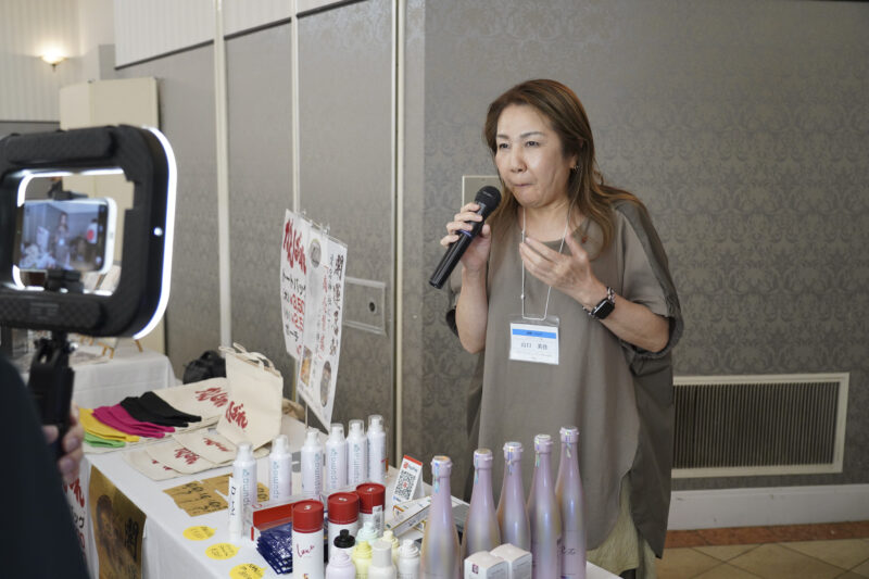 展示商品を前にマイクで事業を紹介する参加者